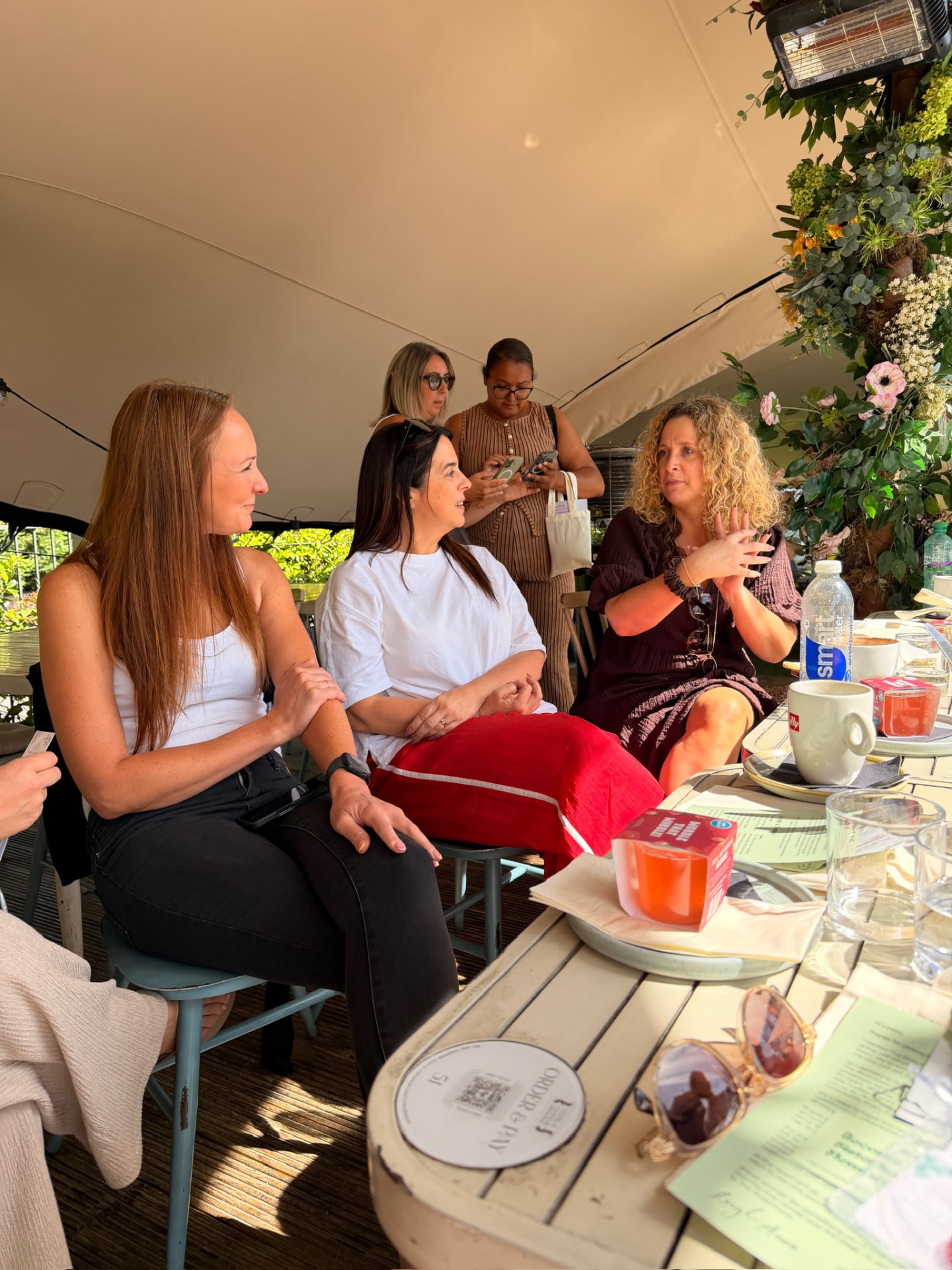 Three women deep in conversation at an outdoor catch-up table