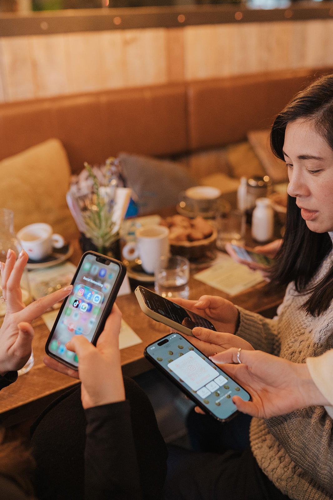 Women swapping social handles on their phones across a cafe table